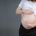 A beautiful pregnant woman on a gray background.